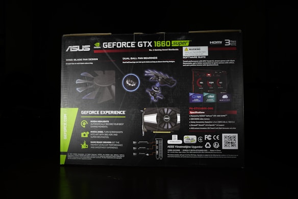 The image features the packaging of an ASUS GeForce GTX 1660 Super graphics card. The box highlights various features such as 'Wing-Blade Fan Design', 'Dual Ball Fan Bearings', and 'Geforce Experience'. It includes visuals of the fan blades and bearing components alongside descriptions of product specifications and software suite capabilities. The packaging is predominantly black with green accents and white text.