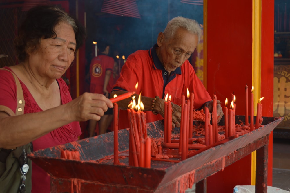 man in red polo shirt holding lighted candles
