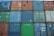 A stacked arrangement of colorful shipping containers, each marked with various numbers and logos. The containers display signs of wear and rust, indicating frequent use, and are arranged in a tight grid pattern.