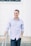 man in blue dress shirt standing near white wall