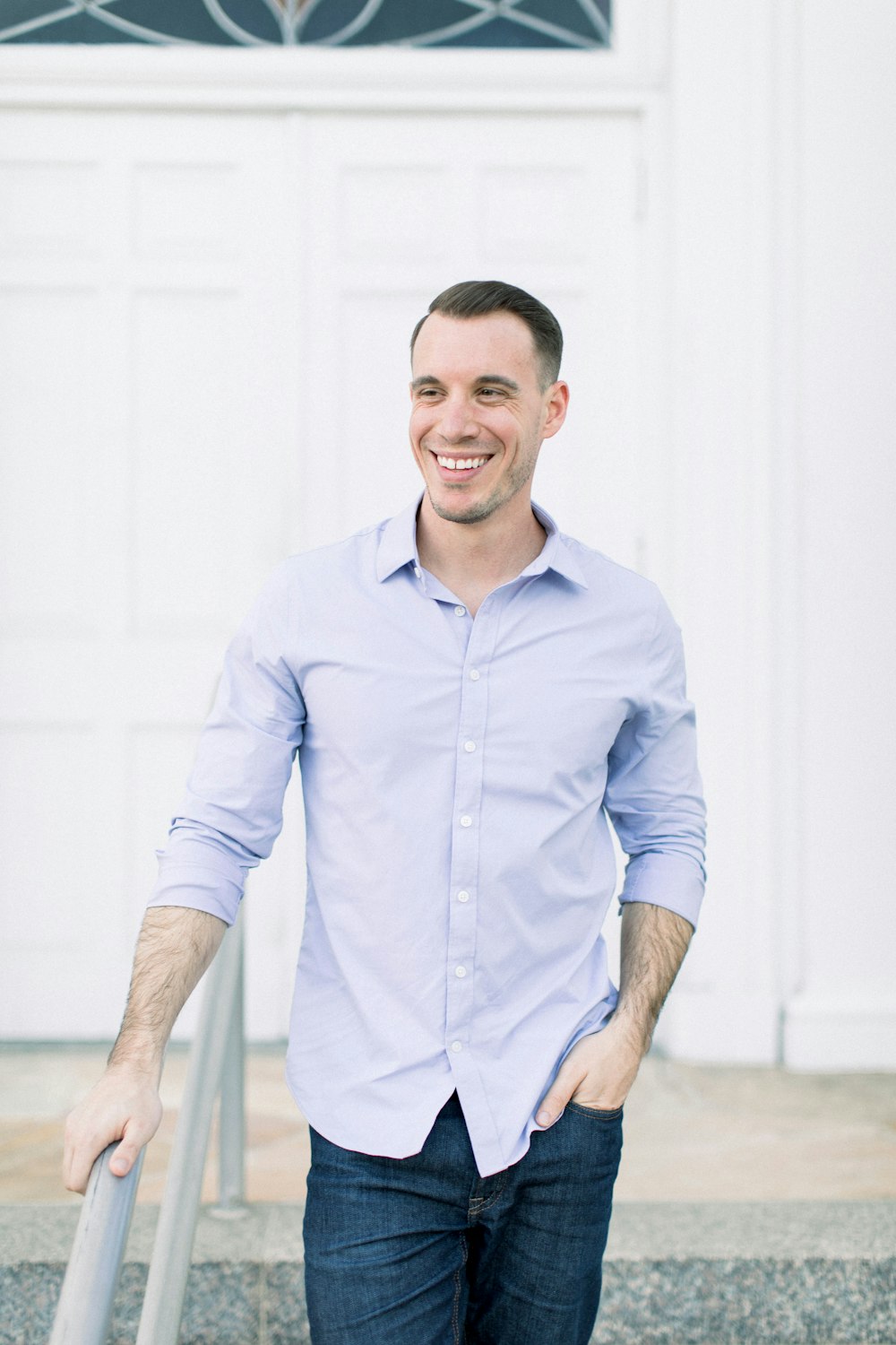 man in blue dress shirt standing near white wall