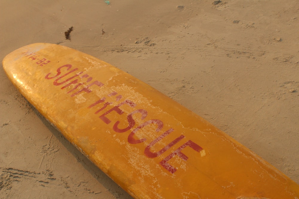 yellow and red surfboard on white sand