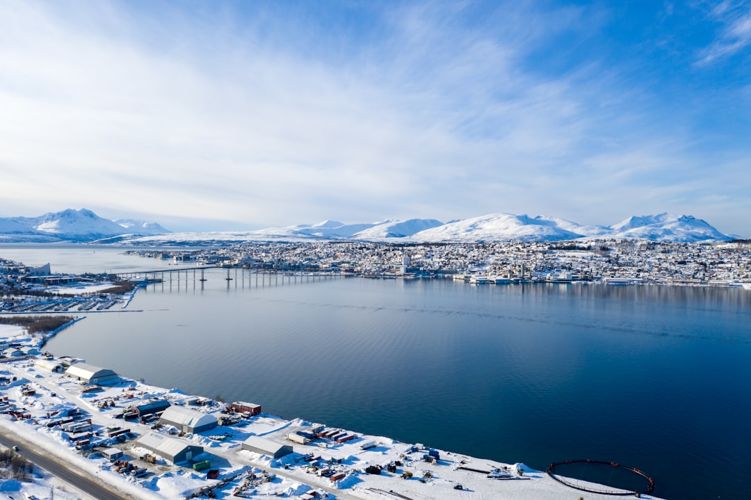 white and blue houses near body of water under white clouds and blue sky during daytime