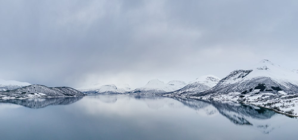 snow covered mountain near body of water during daytime