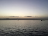 A panoramic view of a dark-hulled crude oil tanker gliding through calm, twilight seas under a navy sky.