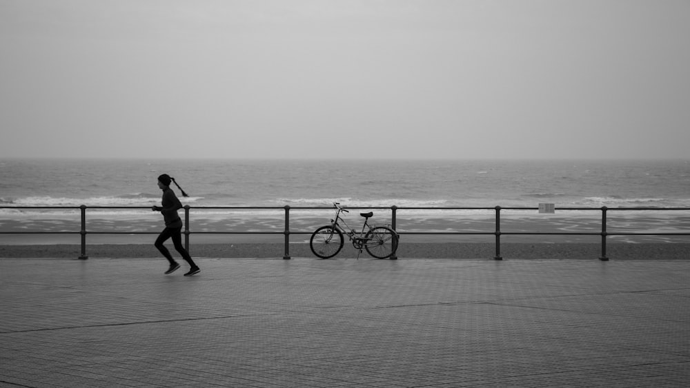 grayscale photo of man and woman walking on the beach