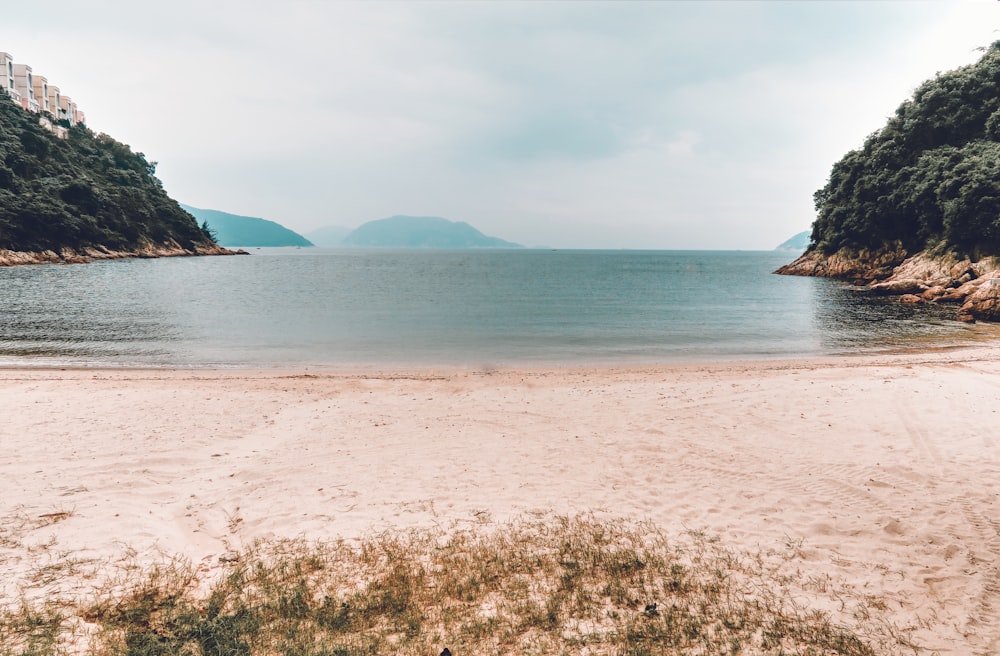 person in brown hat standing on brown sand near body of water during daytime