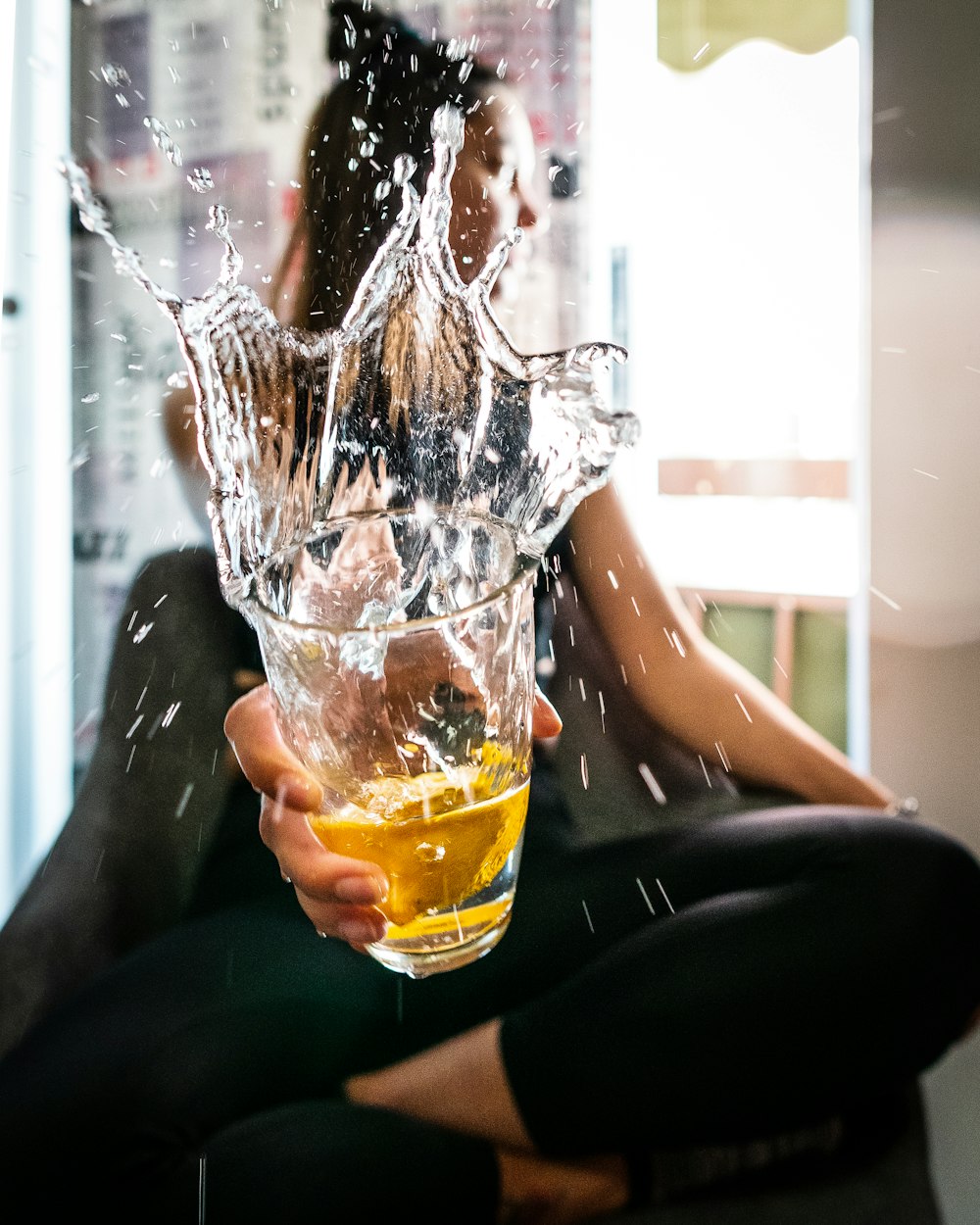 person pouring yellow liquid on clear drinking glass