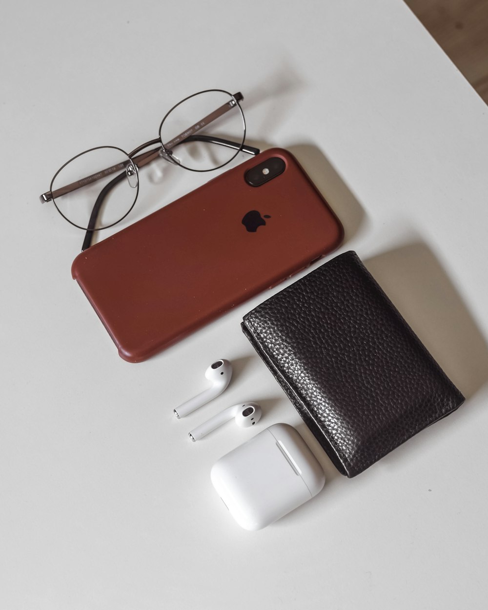赤と黒のiPhoneケース、白い革の財布の横