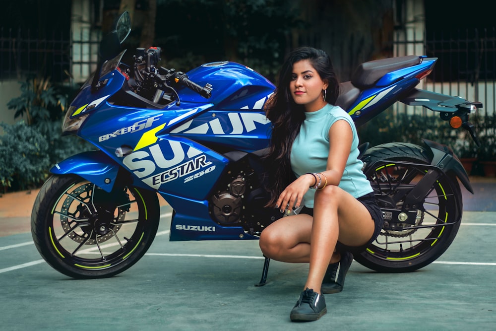 woman in white t-shirt sitting on blue and black sports bike