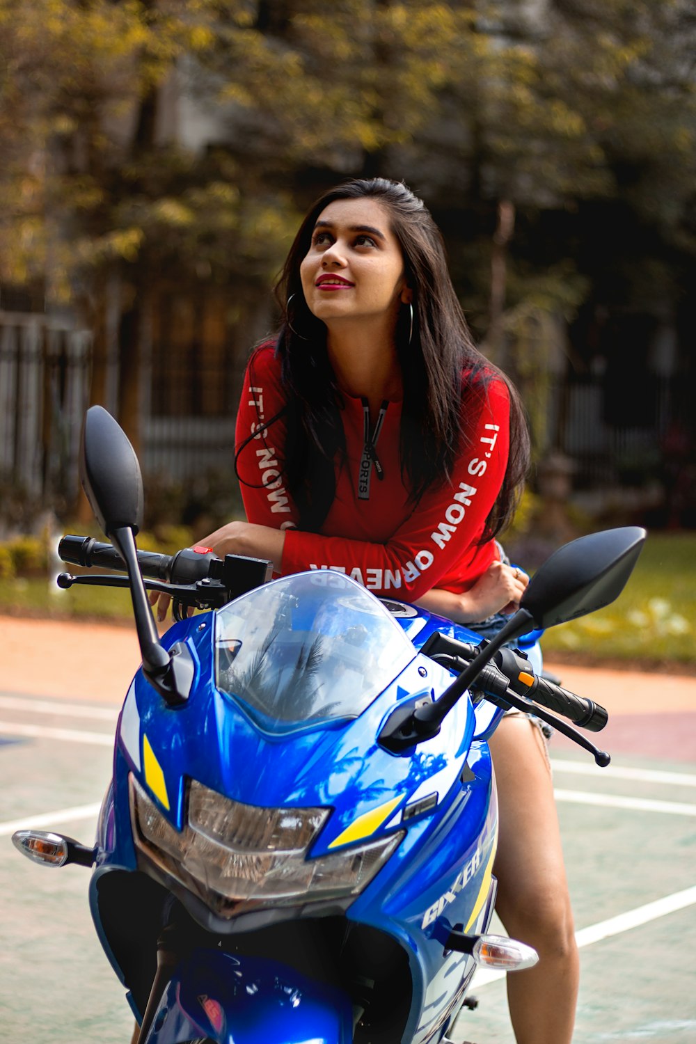 woman in red jacket riding blue and black sports bike