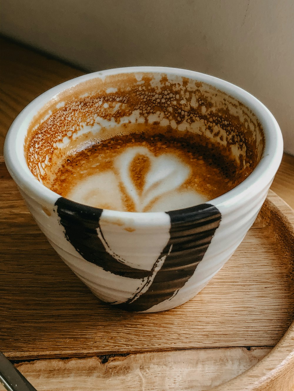 white and black ceramic cup with brown liquid