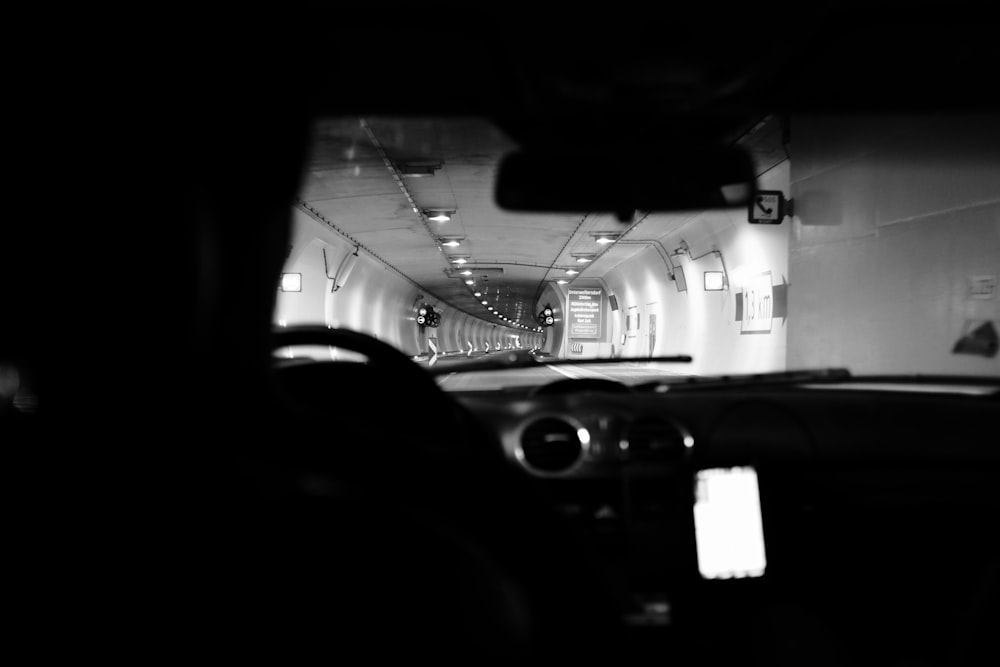 a black and white photo of a car driving down a tunnel