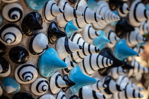 A collection of ceramic or plastic cone shapes arranged in a pattern. The objects have a glossy finish and come in black, white, and blue colors, with some featuring striped designs.