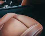Interior shot of a leather-trimmed luxury car cabin with ambient bronze lighting.