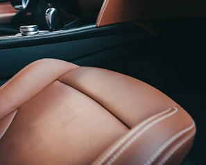 Interior shot of a leather-trimmed luxury car cabin with ambient bronze lighting.