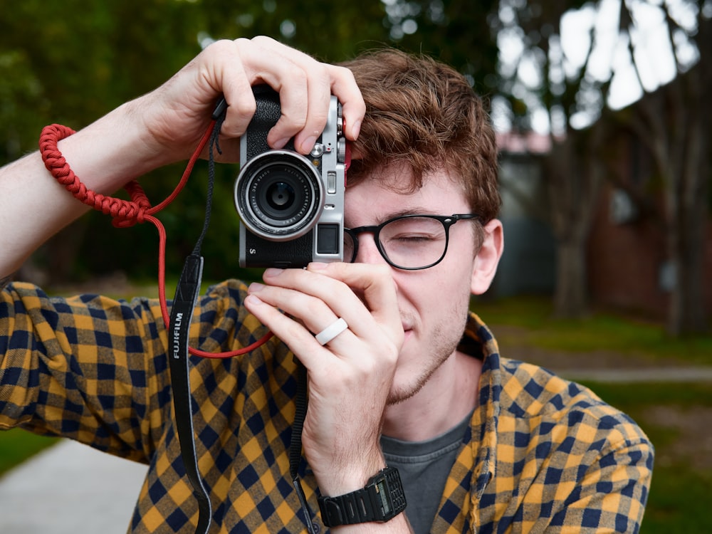 man in black framed eyeglasses holding black and silver camera