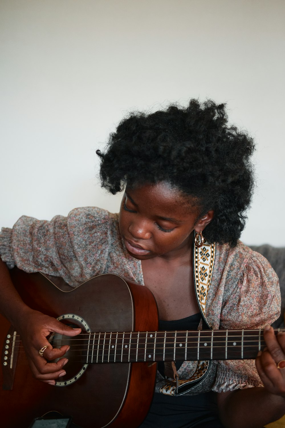Mujer con camisa marrón y negra con estampado de leopardo tocando la guitarra acústica