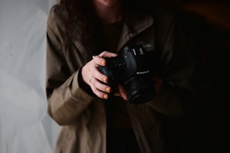 woman in brown coat holding black dslr camera