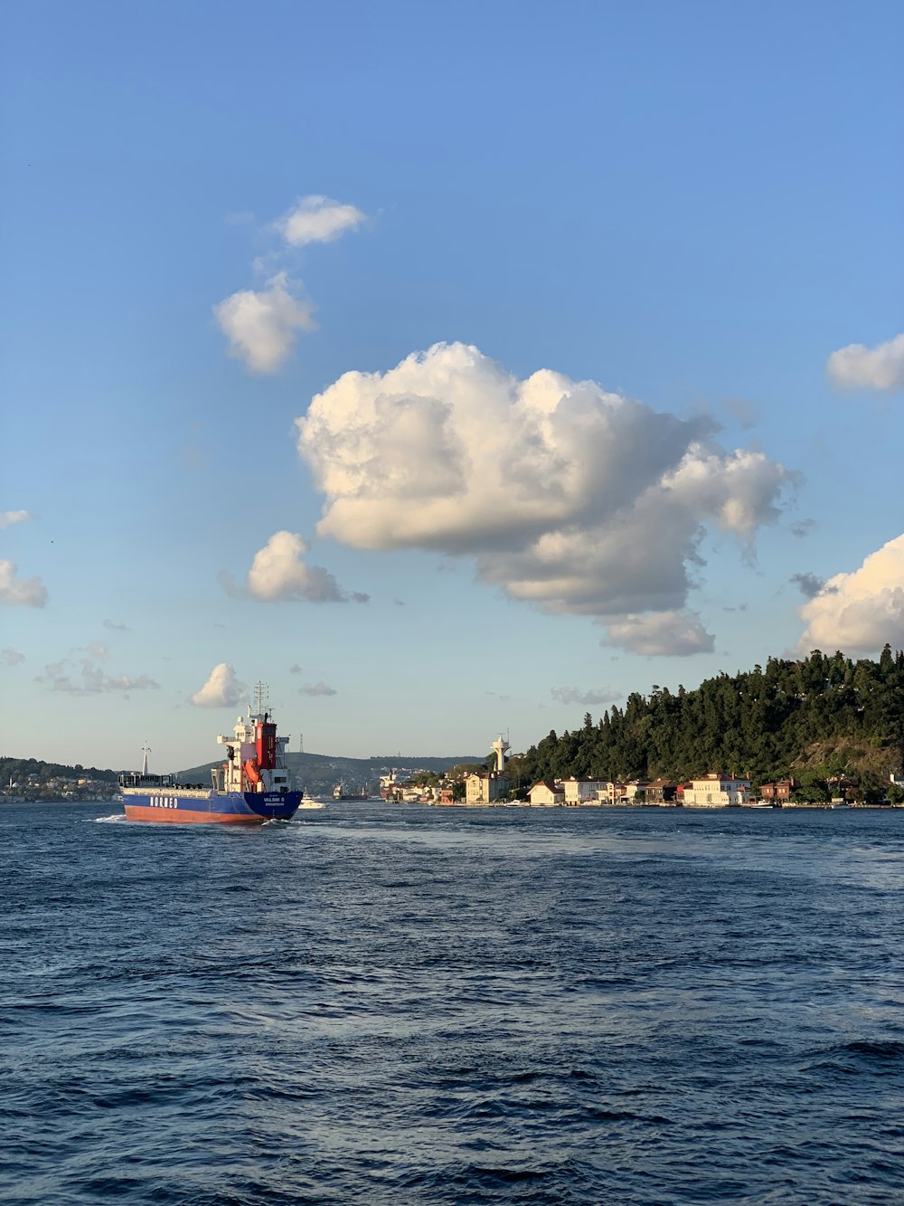 red and white boat on sea under blue sky and white clouds during daytime