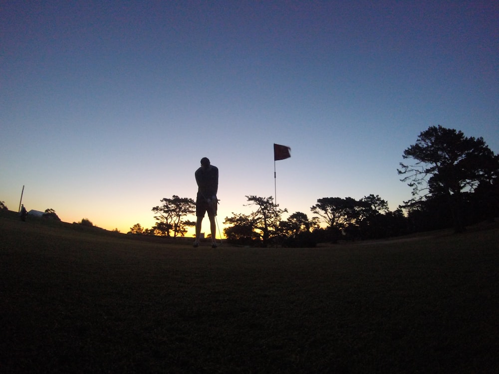 silhouette of man and woman standing on grass field during sunset