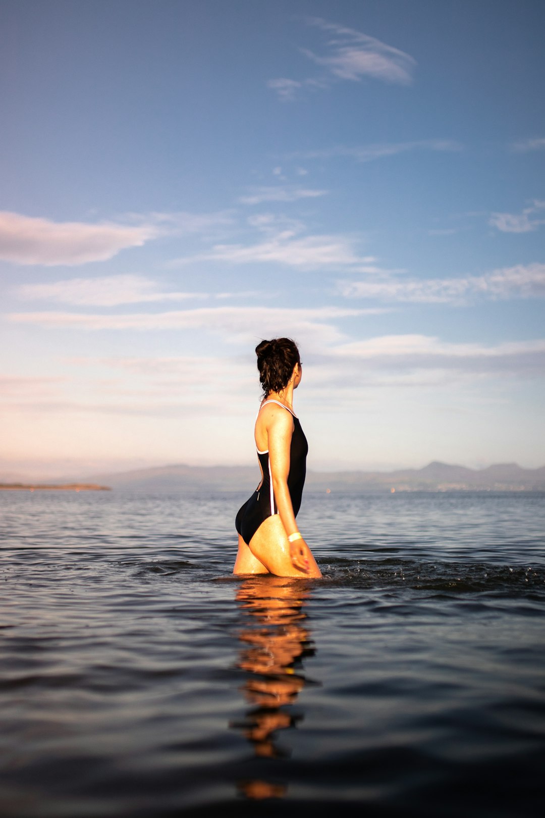 woman in black bikini bottom sitting on water during sunset