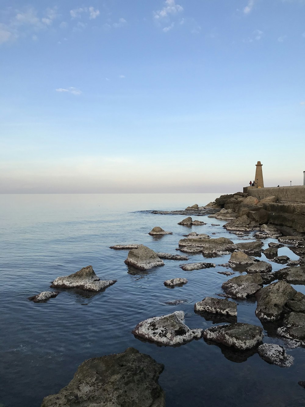 brown and white lighthouse on rocky shore during daytime