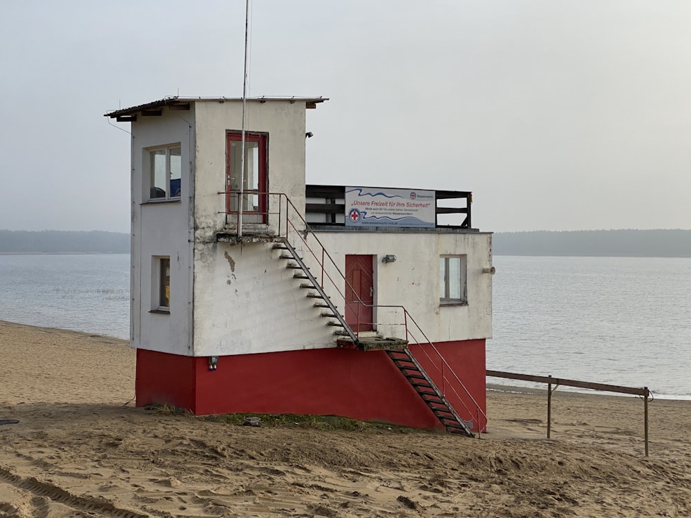 white and red wooden house near body of water during daytime