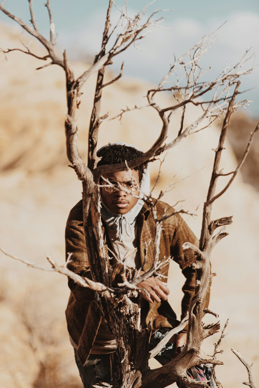 man in brown coat holding brown tree branch