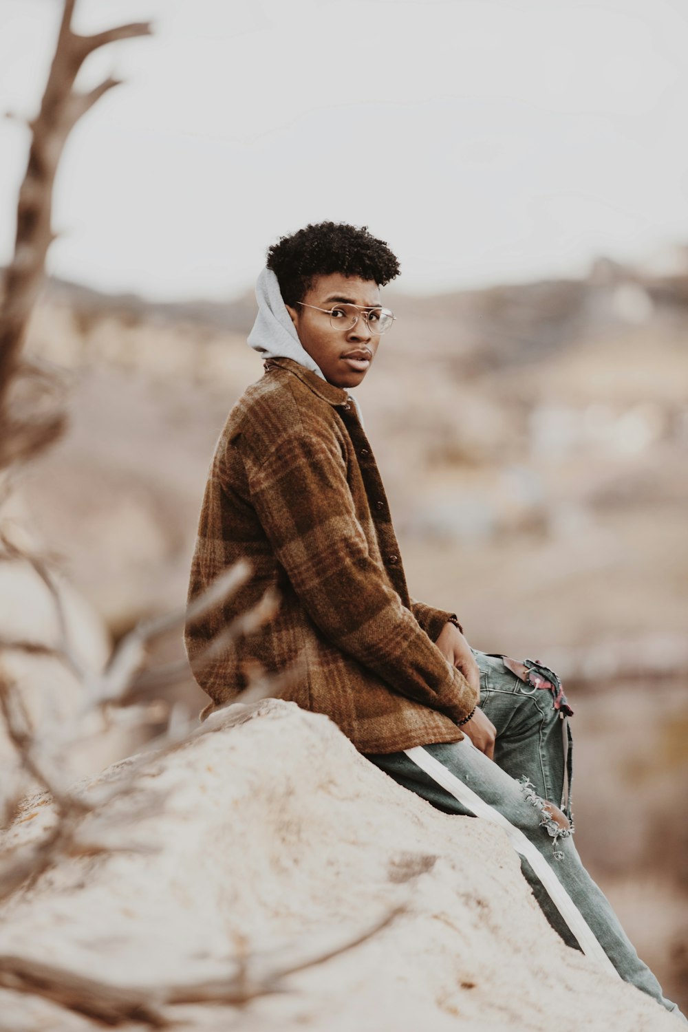 man in red and brown plaid dress shirt sitting on rock during daytime