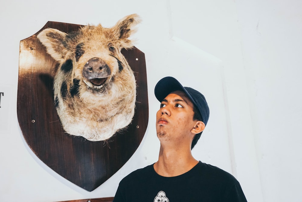 man in black crew neck shirt beside brown and white cow