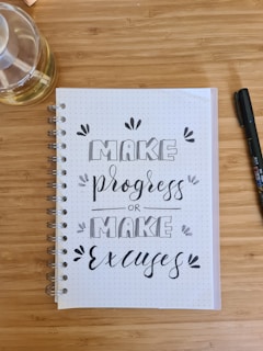 A journal and pen on a wooden table, symbolizing tracking progress and motivation