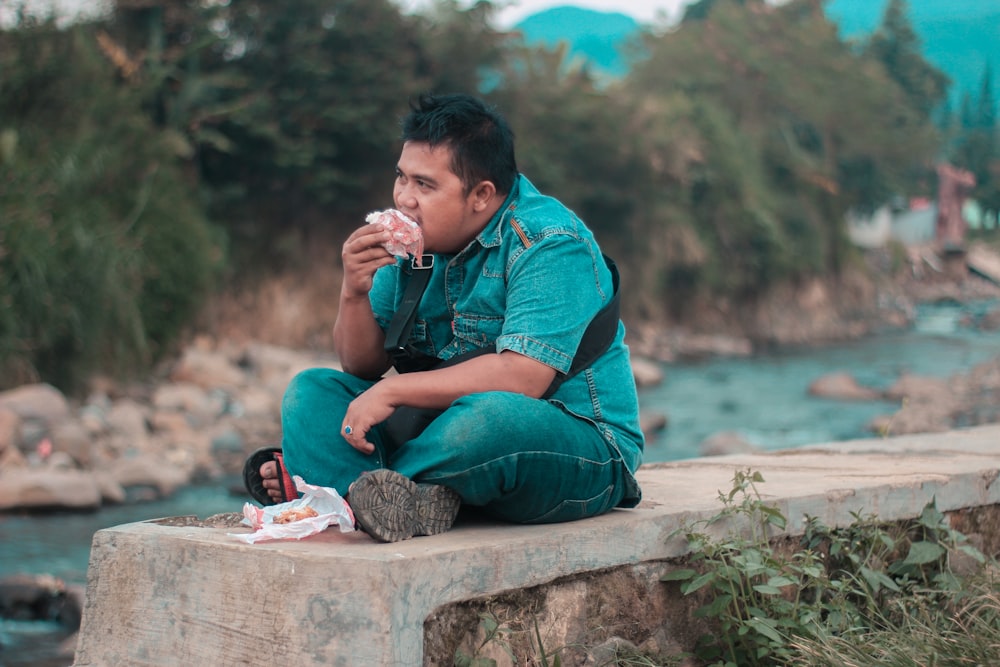 a man sitting on a ledge eating a donut