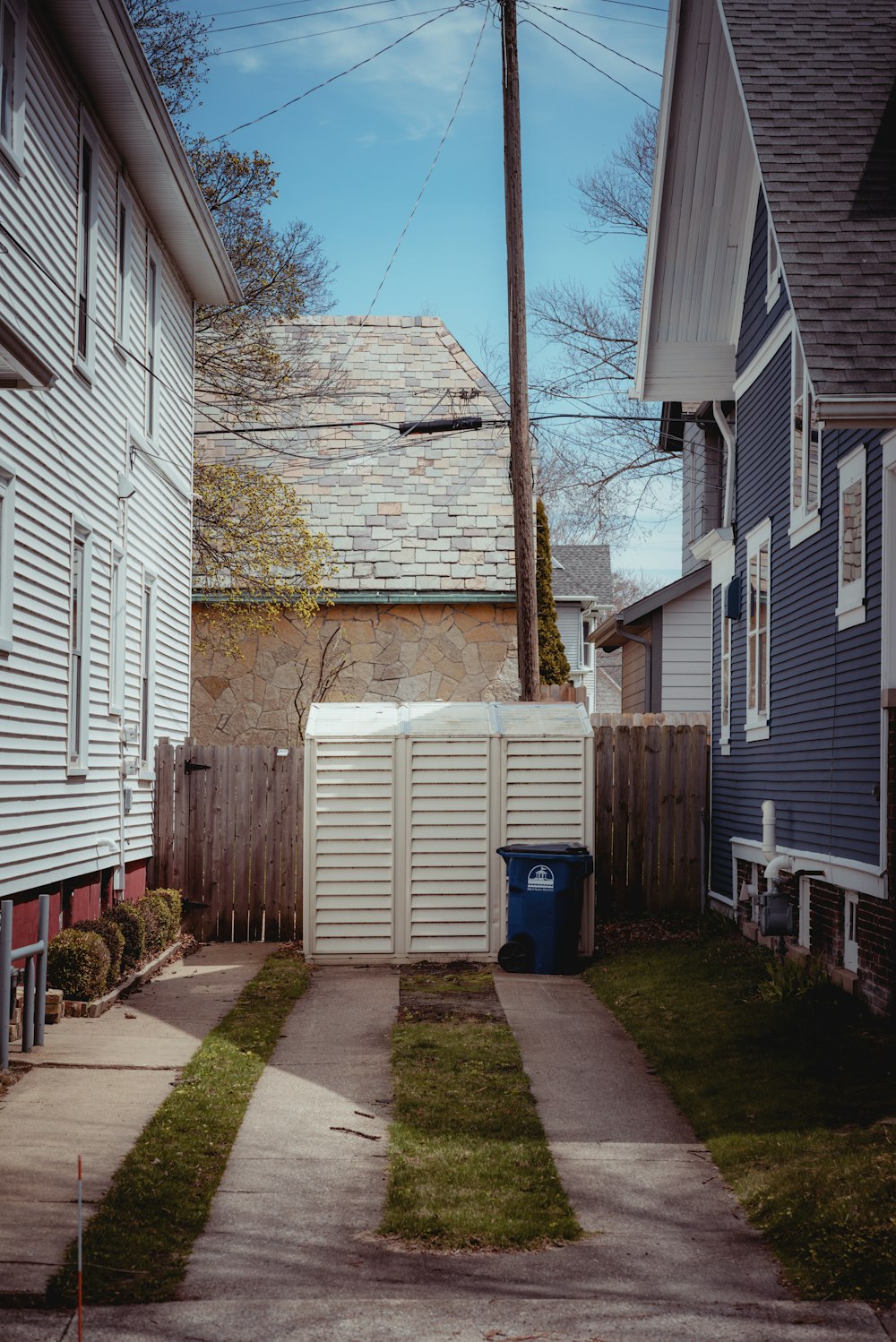 blue plastic trash bin beside brown brick wall