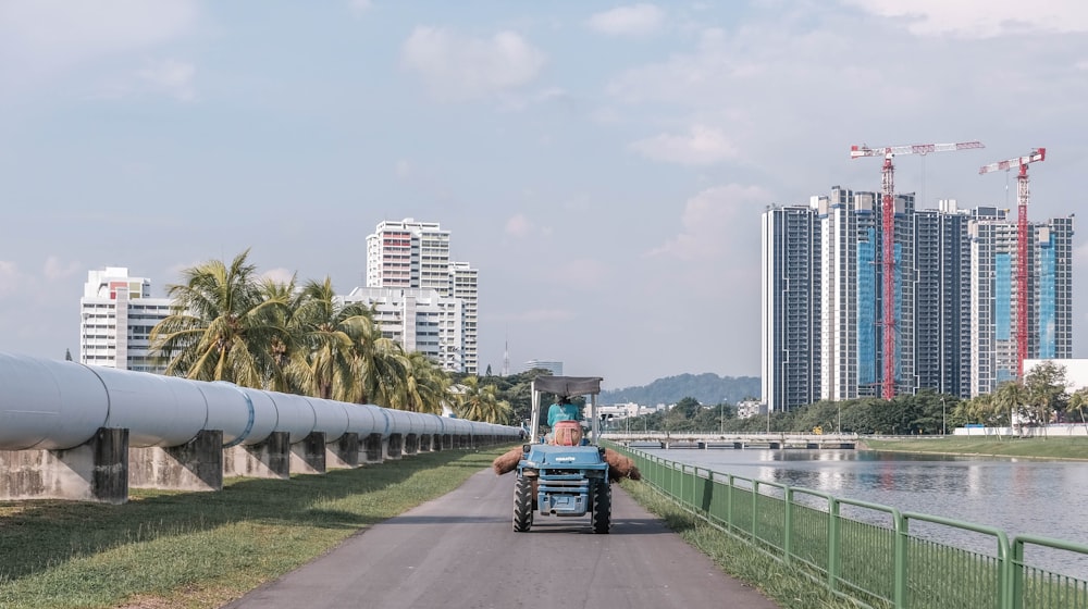 blue and black tractor on gray concrete road near city buildings during daytime