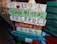 Colorful wooden signs with various languages, including Chinese, Korean, and English, are stacked on a pole. They are painted in bright colors with different messages and symbols.