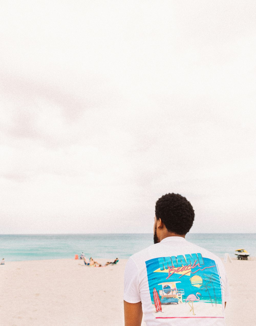 man in white and blue crew neck t-shirt standing on beach during daytime