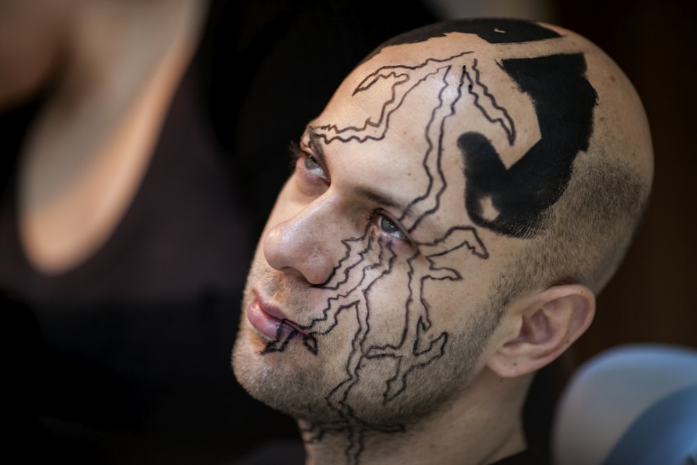 man with black and white skull face tattoo