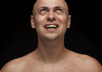 Close-up of a man smiling confidently after a hair replacement treatment in a luxurious black and gold studio.