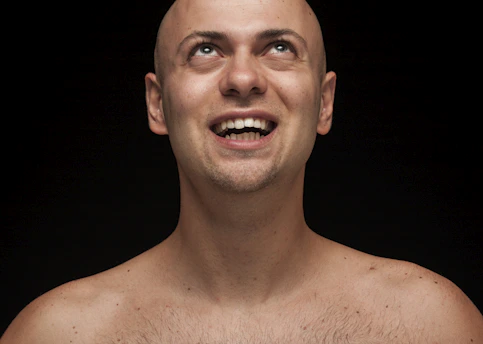 Close-up of a man smiling confidently after a hair replacement treatment in a luxurious black and gold studio.