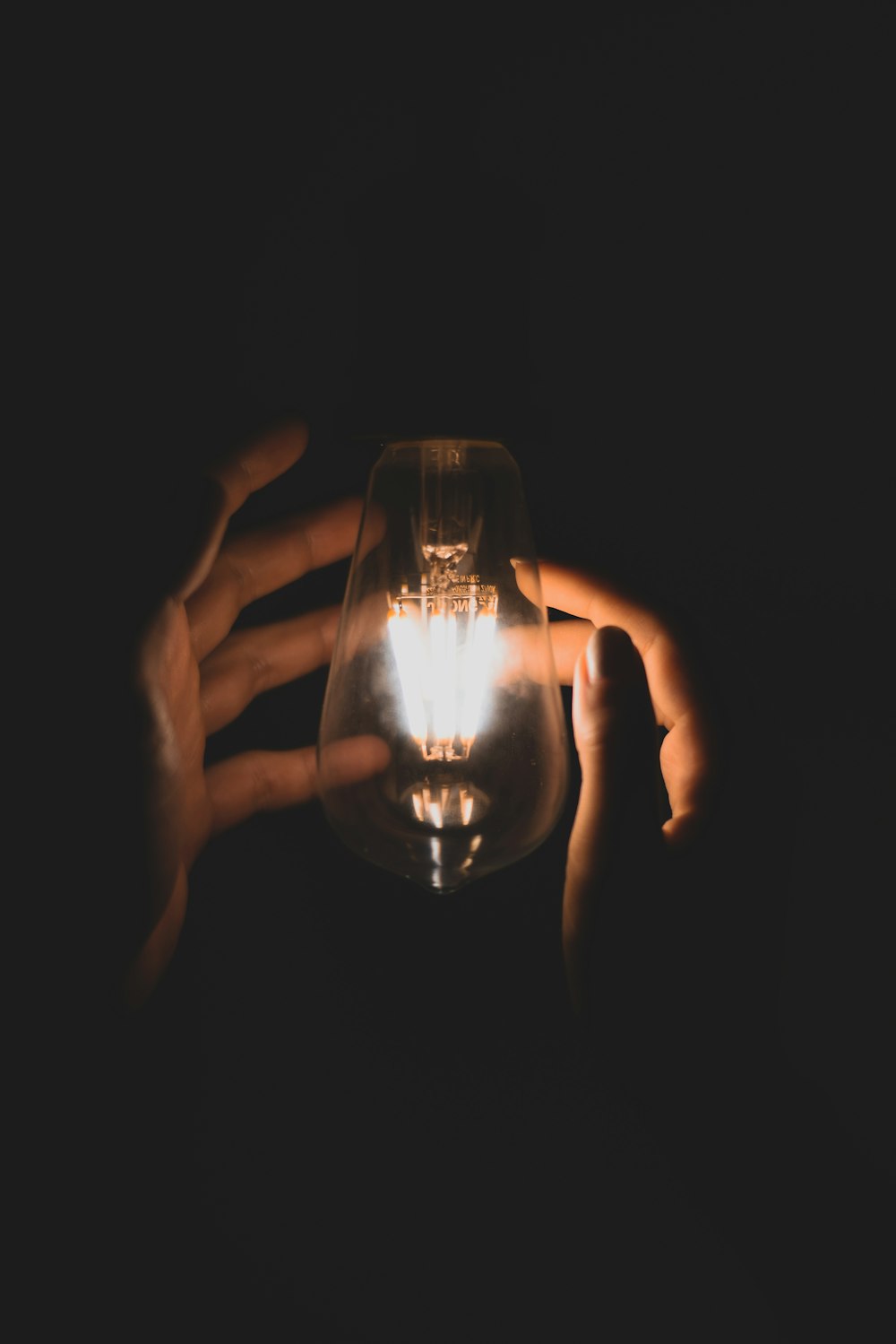 person holding clear glass cup with light