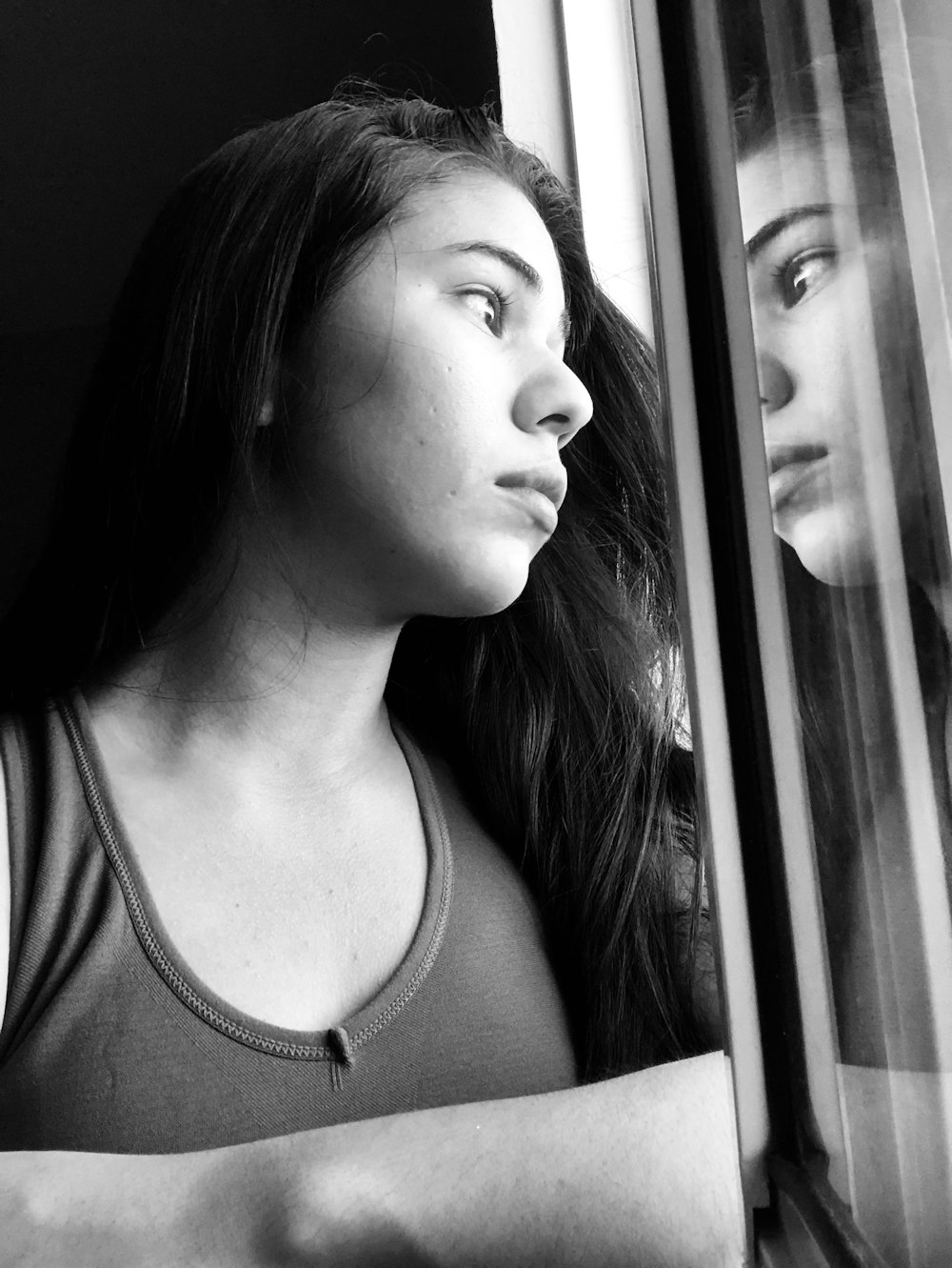 woman in tank top looking out the window