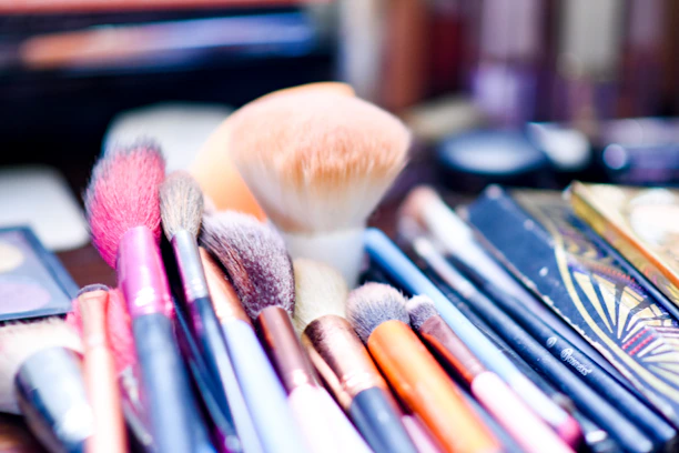 Soft-focus shot of makeup brushes and palettes arranged artistically on a warm-toned surface.