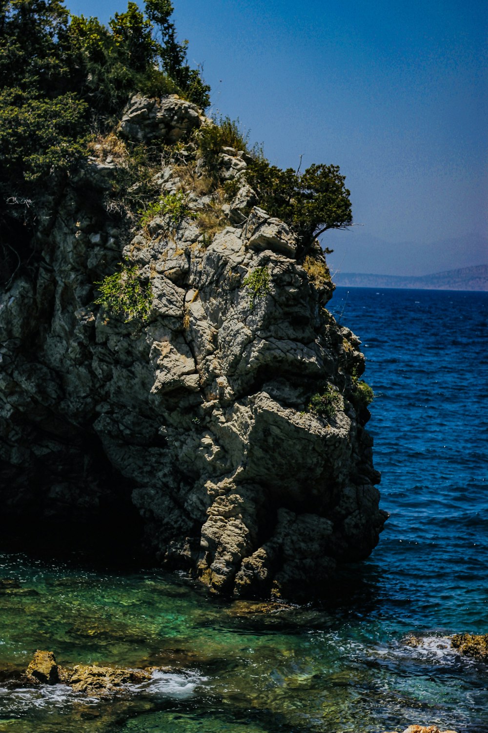 gray rocky mountain beside blue sea during daytime