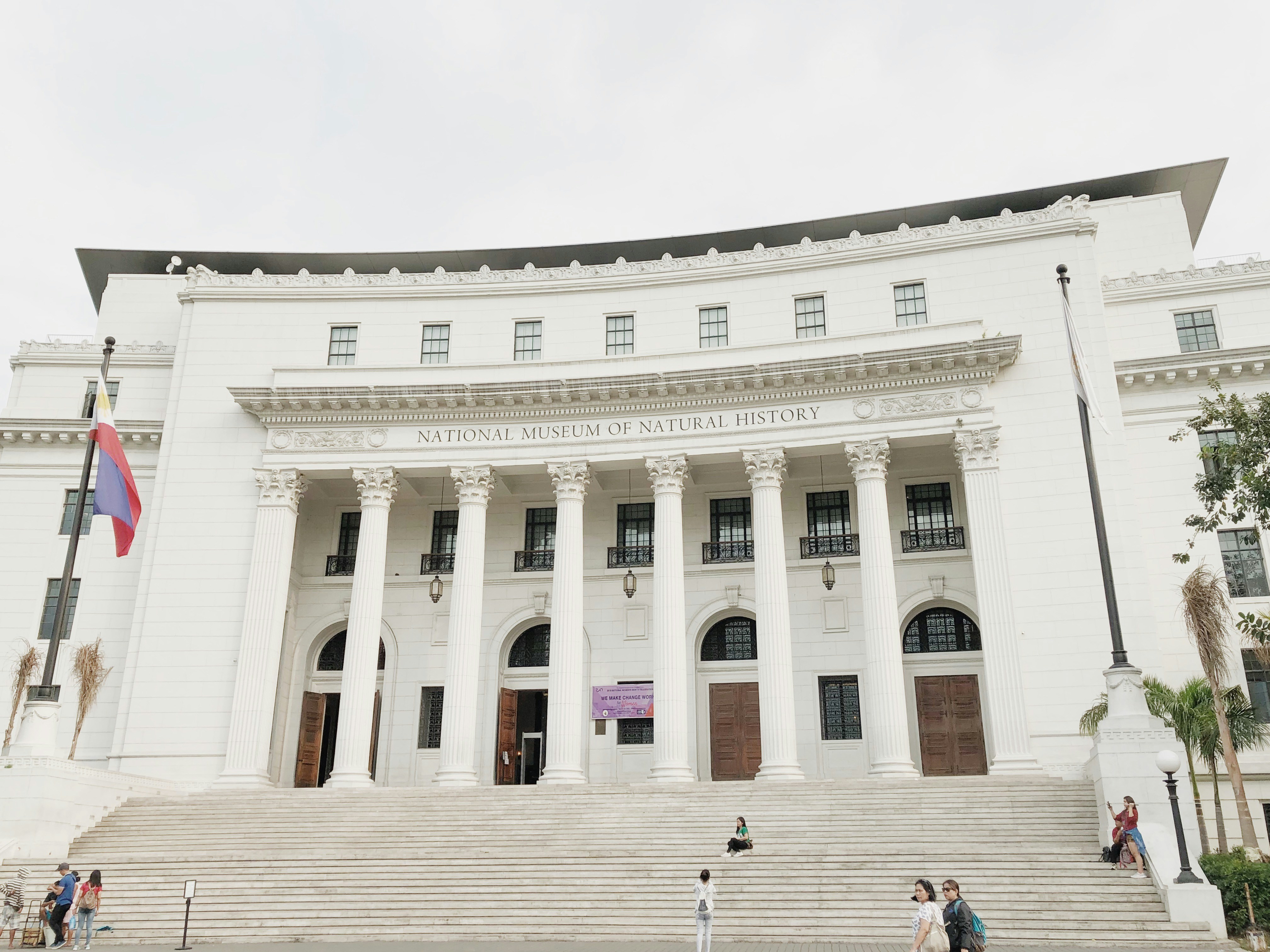 people walking in front of white concrete building during daytime