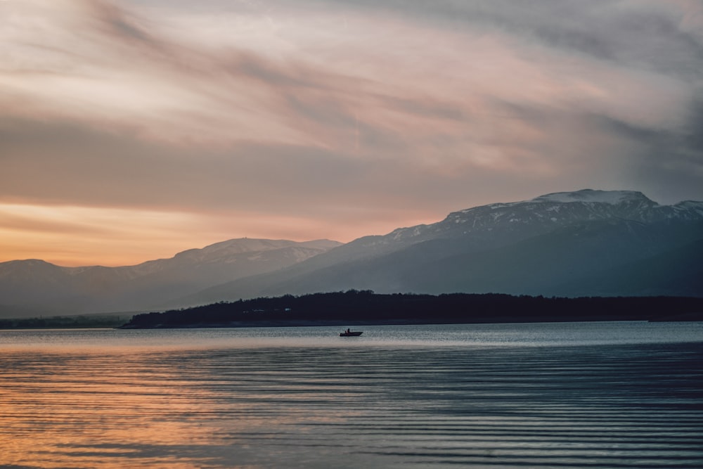 body of water near mountain during daytime