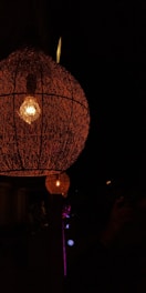 Close-up of a handcrafted wooden mosaic lamp glowing softly in a dark room.