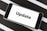 A smartphone displaying the word 'Update' on its screen is placed on a black and white striped surface. The phone is in landscape orientation, and the image focuses on the screen’s content.