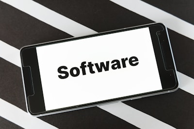 A smartphone is placed on a surface with a black and white striped pattern. The phone screen displays the word 'Software' in bold black text against a white background.