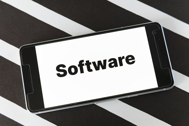 A smartphone is placed on a surface with a black and white striped pattern. The phone screen displays the word 'Software' in bold black text against a white background.